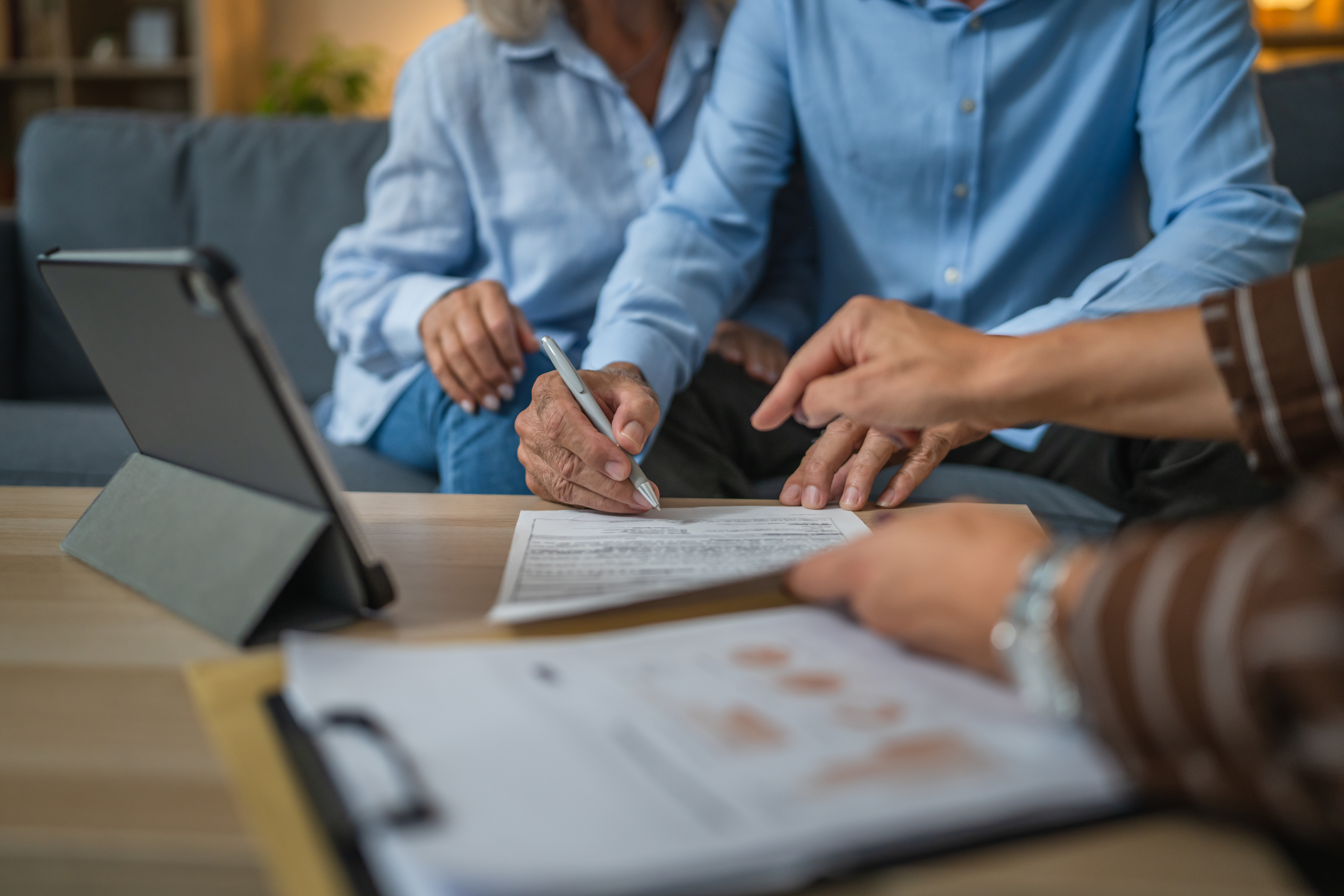 Senior couple sign insurance policy, contract to woman financial adviser at home
